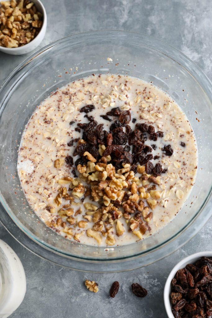 baked oatmeal mixed in bowl and topped with raisins and walnuts
