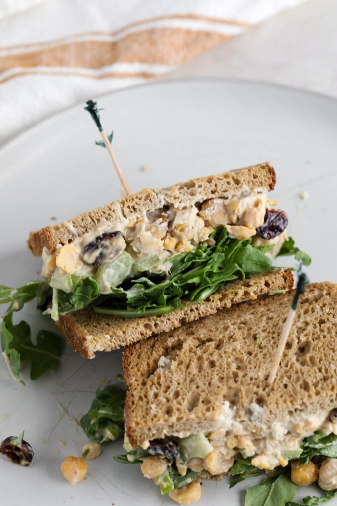 Cranberry Chickpea Salad Sandwich halved and served on white plate