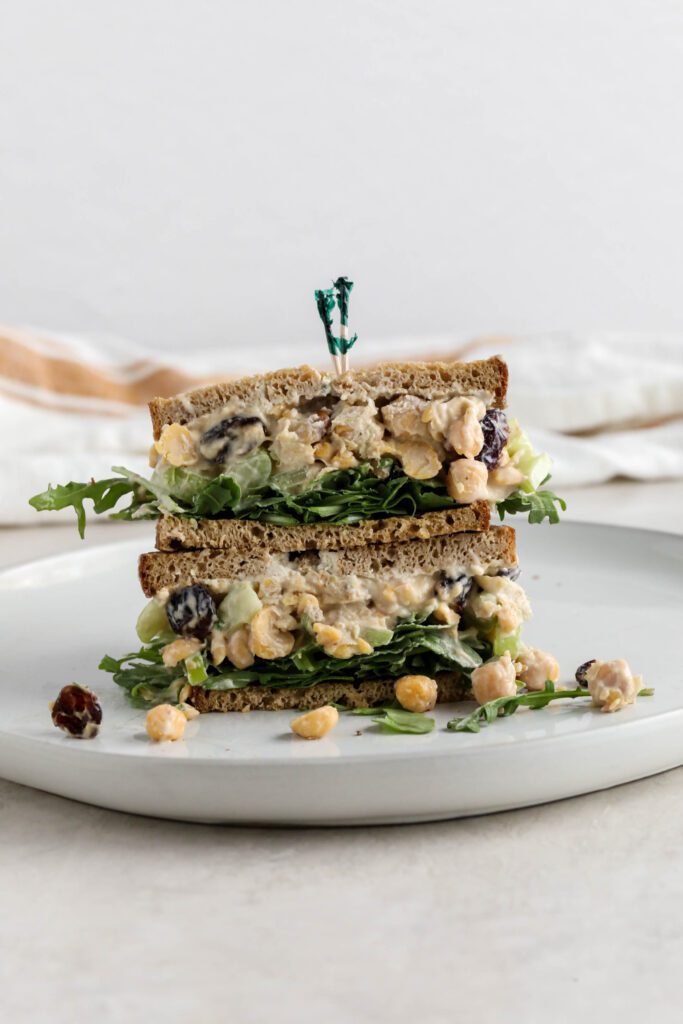 Cranberry Chickpea Salad Sandwich stacked on white plate 