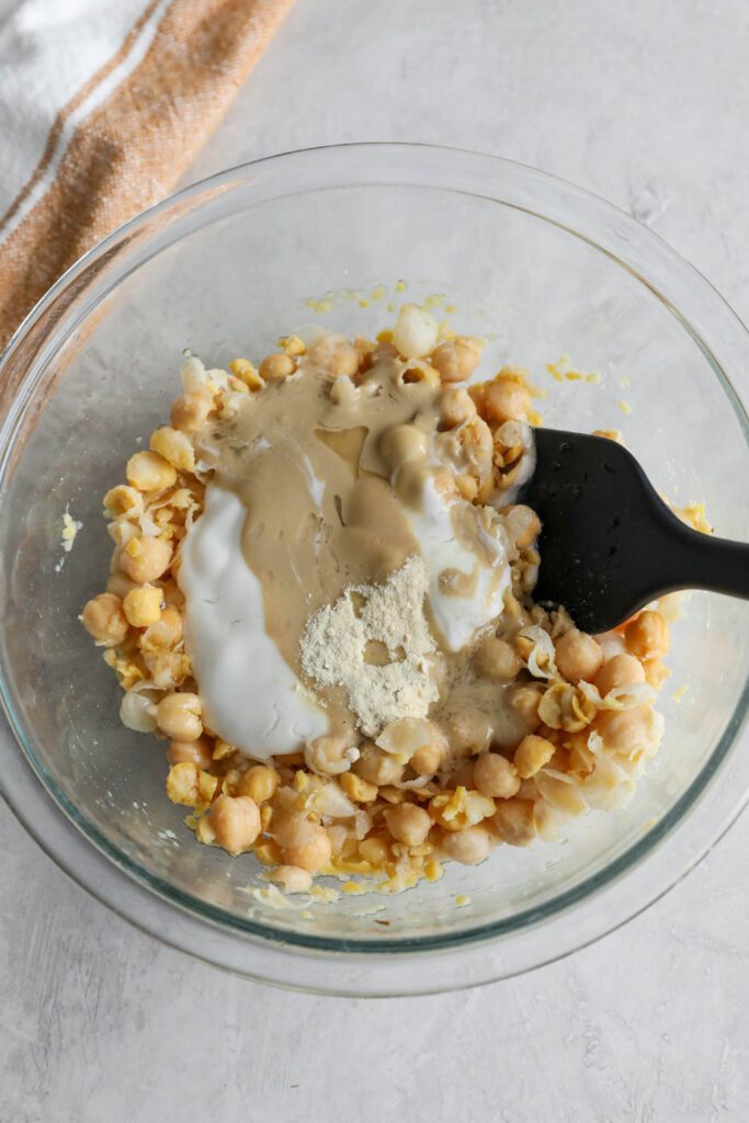 wet ingredients added to smashed chickpeas in bowl 