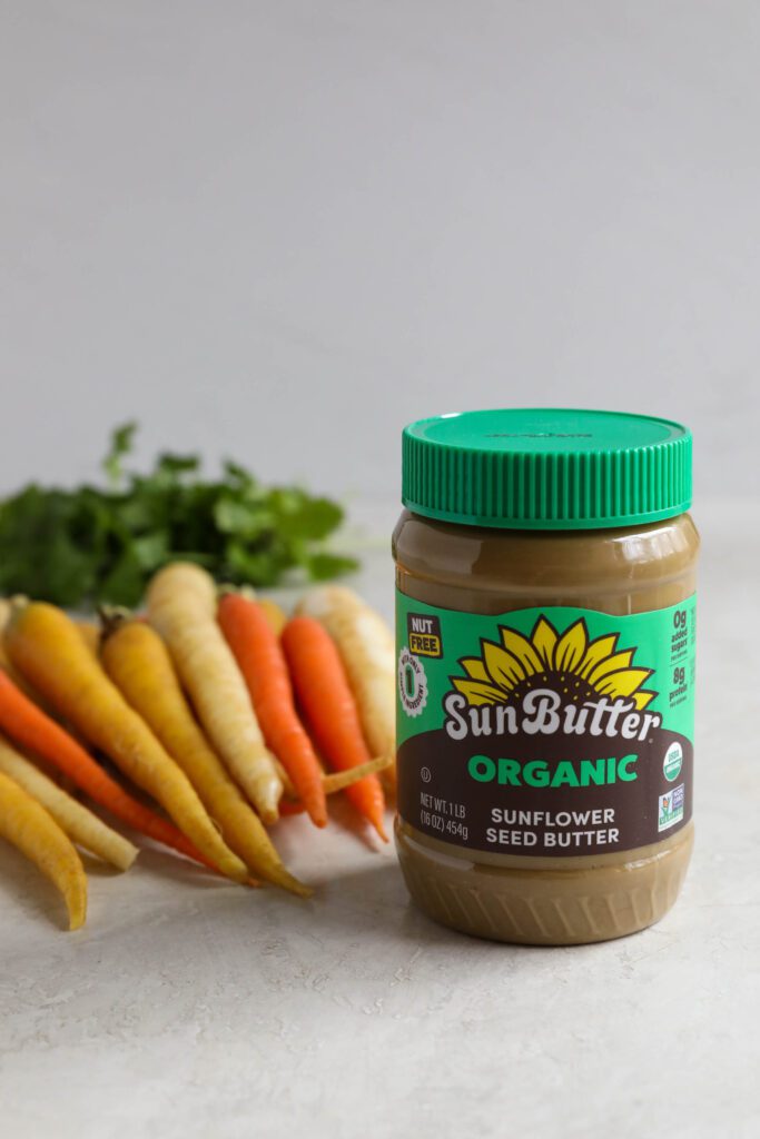 SunButter jar with rainbow carrots and cilantro on board