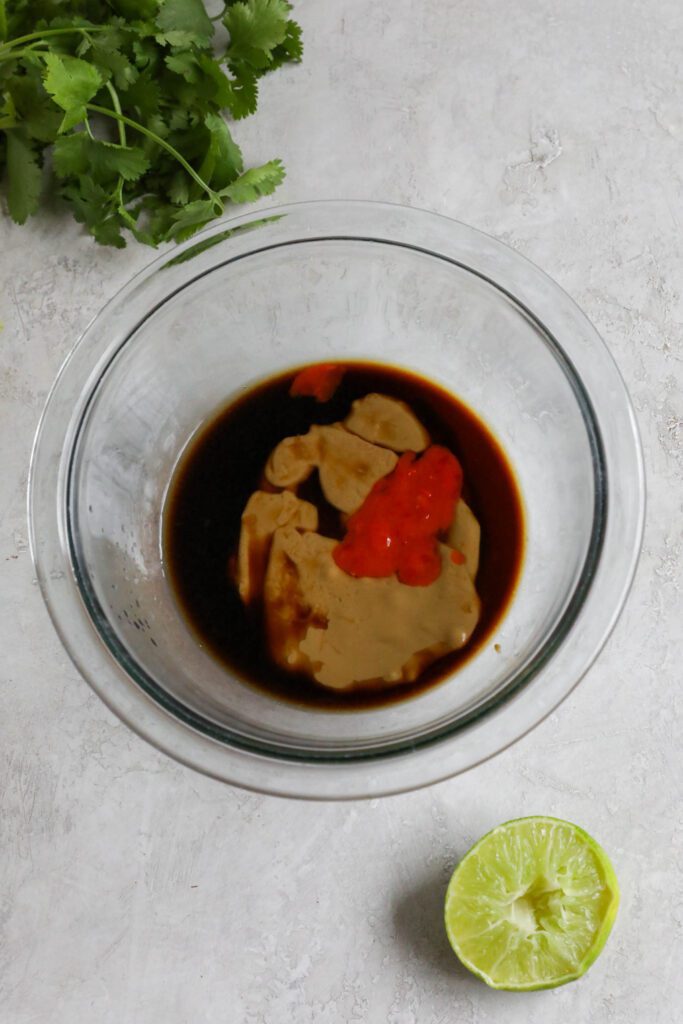 SunButter sauce ingredients in glass bowl with lime and cilantro 
