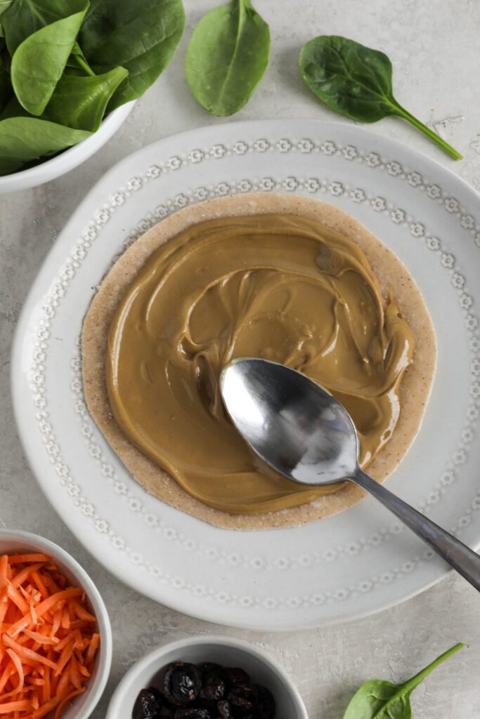 SunButter spread onto tortilla with spoon 