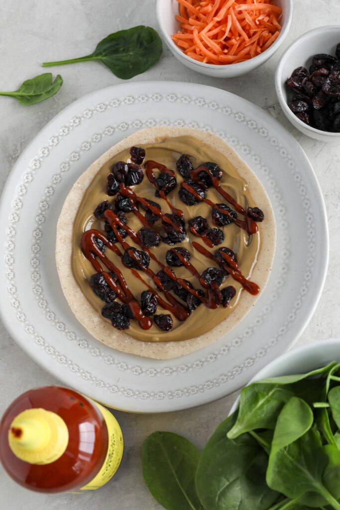 tortilla topped with dried cranberries and sriracha on plate