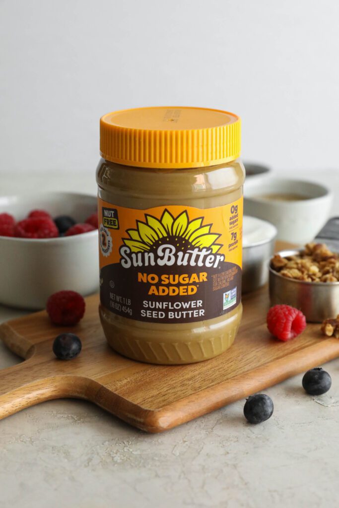 SunButter jar on wooden board with berries and granola