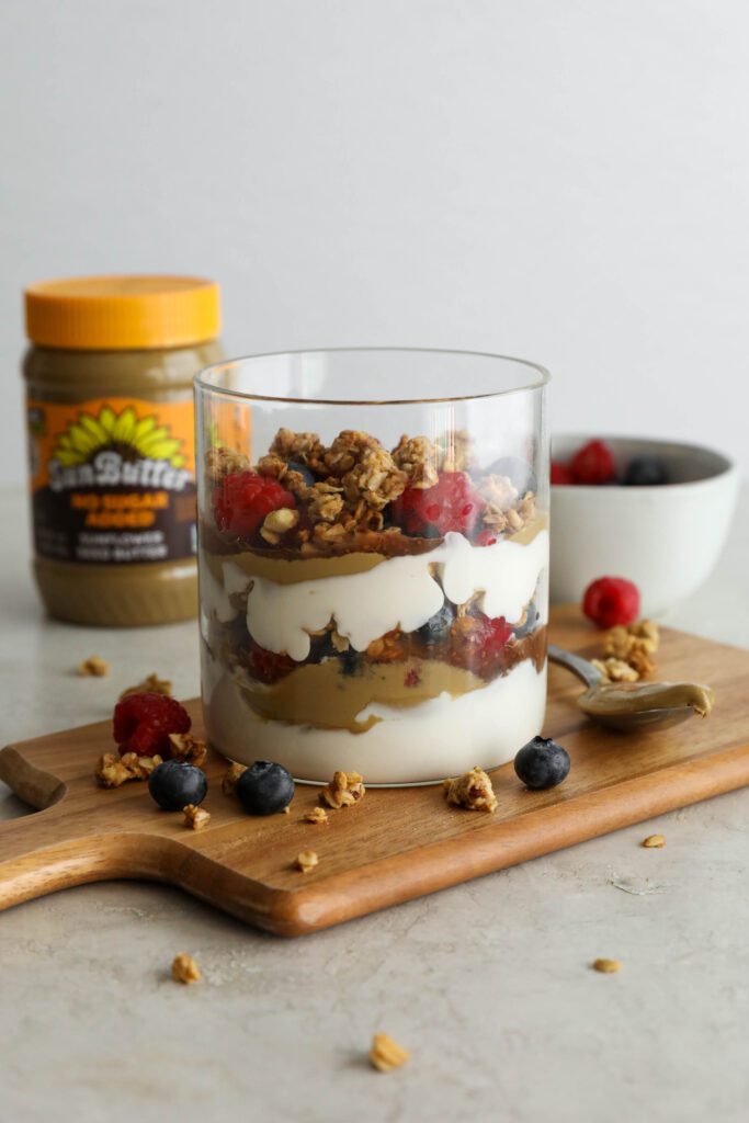 SunButter Berry Spring Parfait in glass jar on wooden board with berries and granola sattered