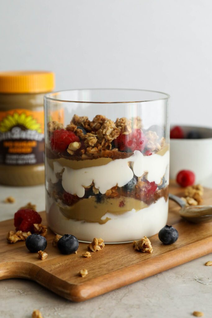 SunButter Berry Spring Parfait in glass jar on wooden board with berries and granola sattered
