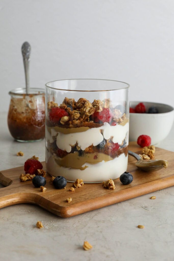 SunButter Berry Spring Parfait in glass jar on wooden board with berries and granola sattered