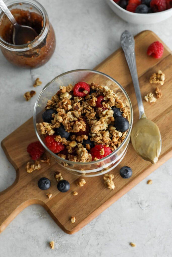 SunButter Berry Spring Parfait in glass jar on wooden board with berries and granola sattered