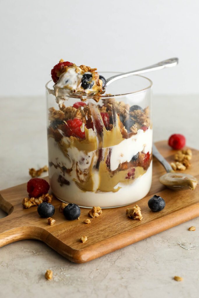 SunButter Berry Spring Parfait in glass jar on wooden board with berries and granola sattered