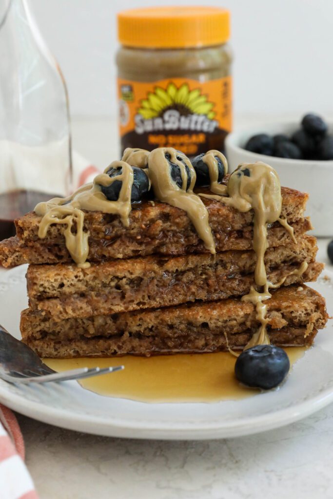 SunButter Stuffed French Toast stacked on plate topped with blueberries and SunButter and maple syrup