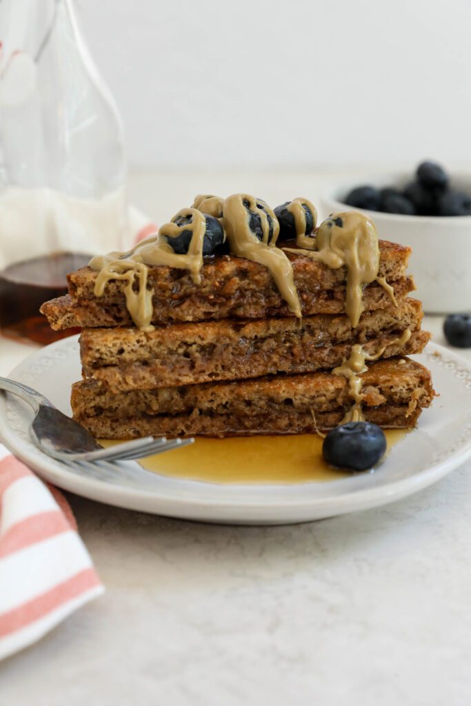 SunButter Stuffed French Toast stacked on plate topped with blueberries and SunButter and maple syrup