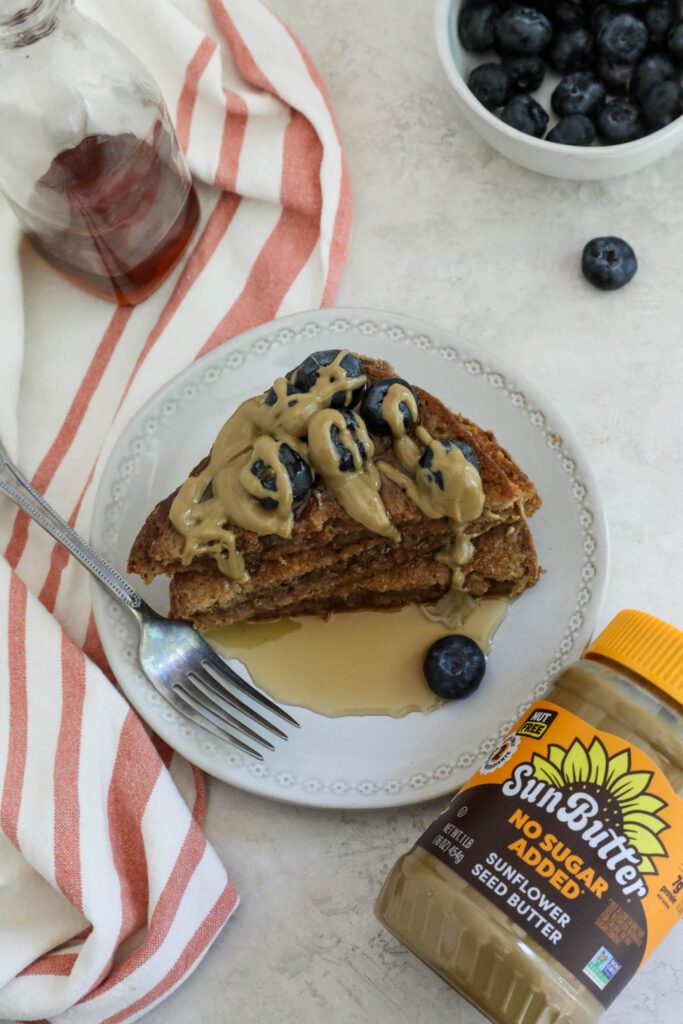 SunButter Stuffed French Toast stacked on plate topped with blueberries and SunButter and maple syrup