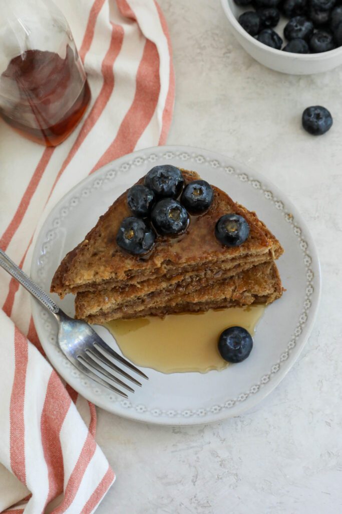 SunButter Stuffed French Toast stacked on plate topped with blueberries and SunButter and maple syrup