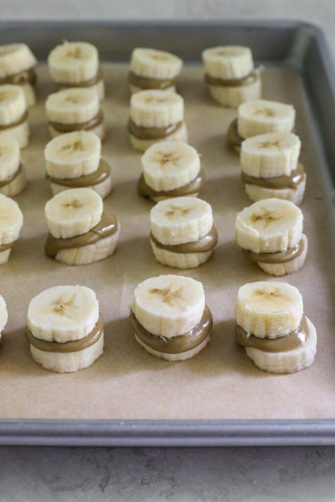 Banana and sunbutter sandwiches on parchment paper lined baking sheet