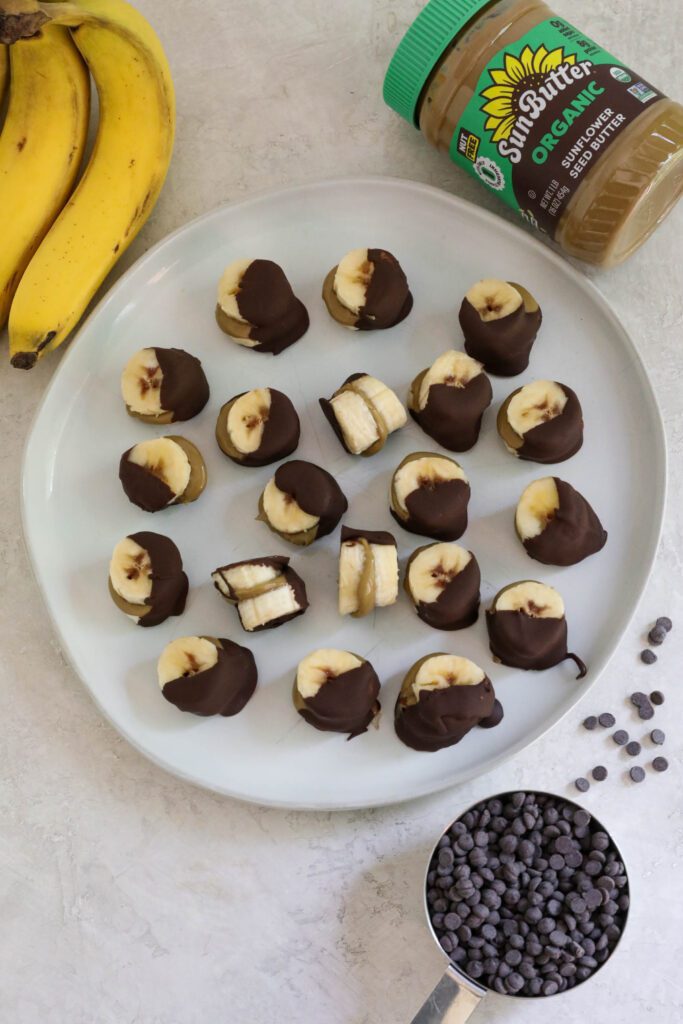 Frozen SunButter Banana Bites on plate with banana, chocolate chips, and SunButter on the side