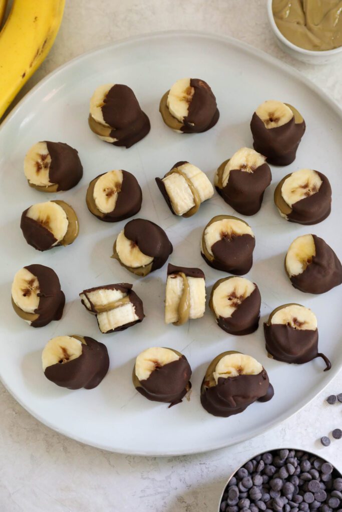 Frozen SunButter Banana Bites on plate with banana, chocolate chips, and SunButter on the side