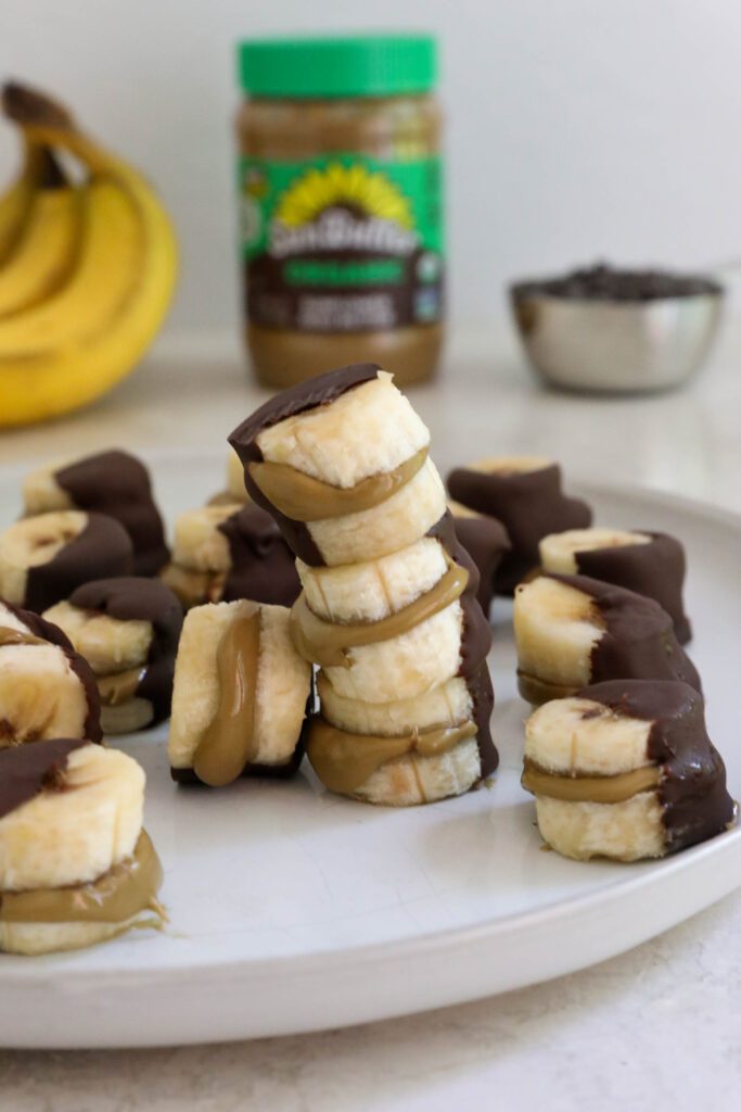Frozen SunButter Banana Bites on plate with banana, chocolate chips, and SunButter on the side